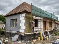 Casă în timpul izolării fațadei, cu plăci de izolație lipite pe zid și schelă