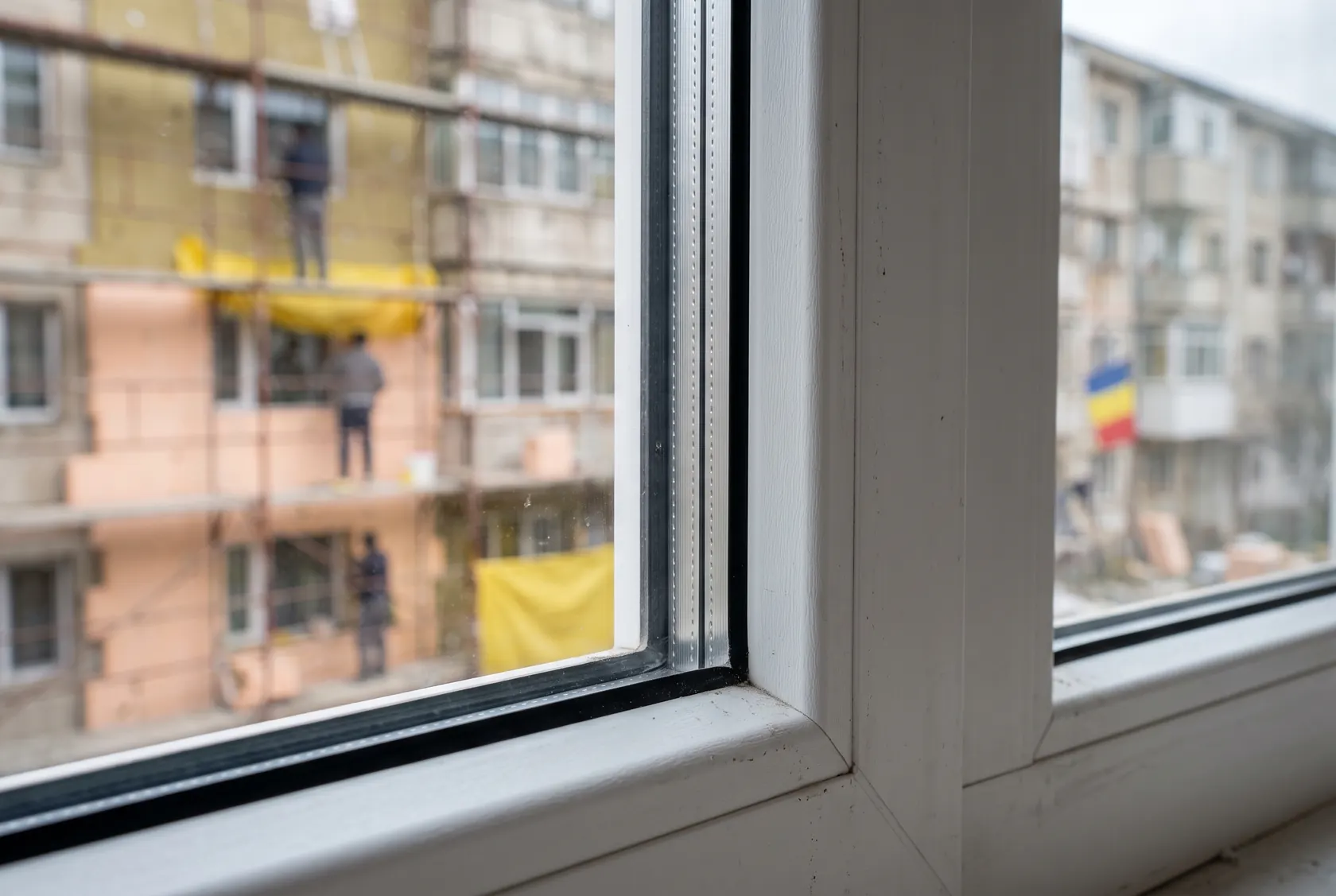 Colțul unui geam triplu cu distanțier închis la culoare și garnitura ramei